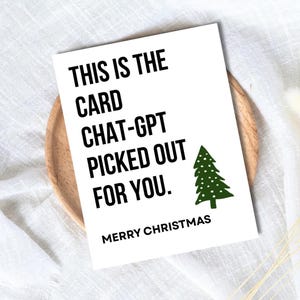 May include: A white Christmas card with black text that reads "THIS IS THE CARD CHAT-GPT PICKED OUT FOR YOU." A green Christmas tree graphic is on the right. The card says "MERRY CHRISTMAS" at the bottom.