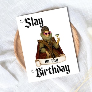 Może przedstawiać: Biała kartka z życzeniami z napisem "Slay on thy Birthday" czcionką gotycką. Karta przedstawia ilustrację w stylu vintage kobiety w renesansowej sukni i różowych okularach przeciwsłonecznych trzymającej koktajl.