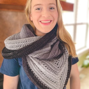 May include: A person wearing a gray and black crocheted shawl with a blue shirt.
