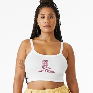 May include: White cropped tank top with a red graphic of cowboy boots and the text "SAVE A HORSE".