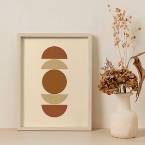 Może przedstawiać: Wydruk w ramie z minimalistycznym geometrycznym wzorem przedstawiającym ułożone na sobie półkola w odcieniach brązu, beżu i pomarańczy na kremowym tle.