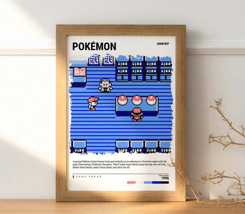 Pu&ograve; includere: Una stampa incorniciata con una scena pixelata del gioco Pok&eacute;mon per Game Boy. L'opera d'arte mostra un ambiente di gioco blu e bianco con personaggi e testo che recita "POK&Eacute;MON" e "GAME BOY". La stampa &egrave; in una cornice di legno.