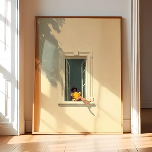 Op de afbeelding: Een ingelijste kunstdruk toont een persoon die een geel boek leest in een zonnig raam. Het kunstwerk gebruikt een warm kleurenpalet met zachte schaduwen en een gedetailleerd architectonisch raamkozijn. De print wordt op een lichtgekleurde muur getoond.