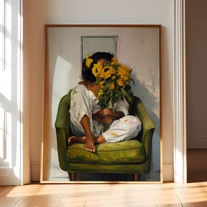 May include: A framed painting depicts a person seated in a green armchair, holding a large bouquet of sunflowers. The person is wearing white pajamas with a floral pattern. The painting is displayed against a white wall, with a wooden floor in the foreground.