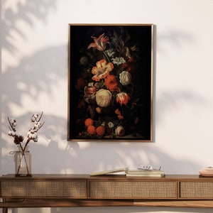 Puede incluir: Una pintura enmarcada de un bodeg&oacute;n con un jarr&oacute;n de flores coloridas, incluyendo tulipes, rosas y claveles, con frutas y hojas en el fondo. La pintura est&aacute; sobre un fondo oscuro y tiene un marco dorado.