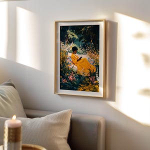 May include: A framed art print depicts a person in a yellow dress reading in a garden. The artwork features a gold frame and is surrounded by lush greenery and colorful flowers. The scene is bathed in natural light.