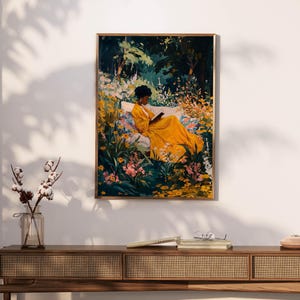 May include: A framed art print depicts a person in a yellow dress reading in a garden. The artwork features a person sitting on a bench surrounded by colorful flowers and lush greenery. The print is displayed on a white wall above a wooden console.