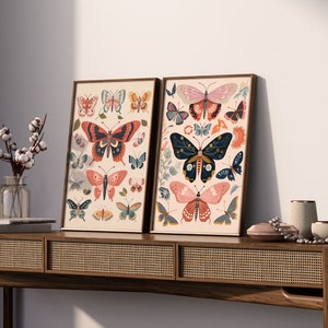 K&ouml;nnte beinhalten: Zwei gerahmte Drucke mit wei&szlig;em Hintergrund und bunten Schmetterlings-Illustrationen. Die Drucke h&auml;ngen an einem Wandregal aus Holz mit einer geflochtenen Rattan-Front.