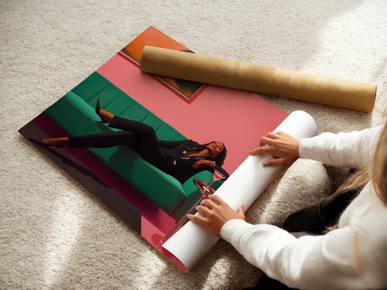 May include: A rolled-up poster and a print featuring a person reclining on a green sofa, with a pink and orange background. The person is wearing a black suit and is holding a glass of wine. The poster is being unrolled.