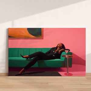May include: A canvas print featuring a person in a black suit relaxing on a green sofa. A cocktail sits on a small side table. The background is a pink wall with an abstract painting.