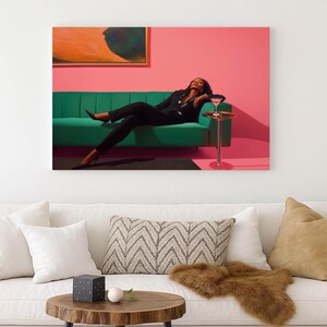 May include: A woman in a black suit reclines on a green sofa against a pink wall. A small side table holds a cocktail. An abstract painting hangs above the sofa. The scene is a stylish, modern interior.