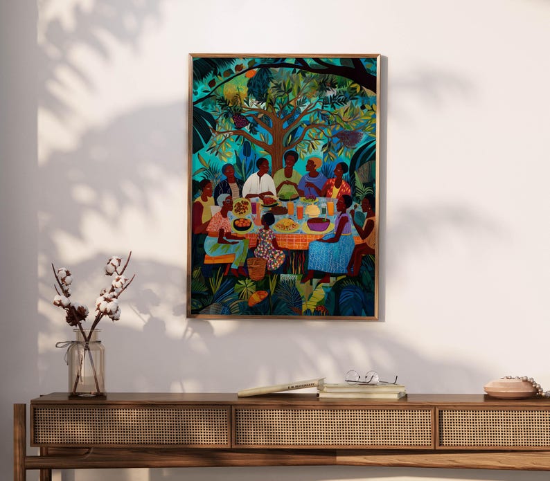 May include: A framed art print showing a colourful outdoor gathering. People are seated around a table with food, under a large tree. The artwork uses a vibrant palette of blues, greens, and oranges, creating a lively scene. The print is in a wooden frame.