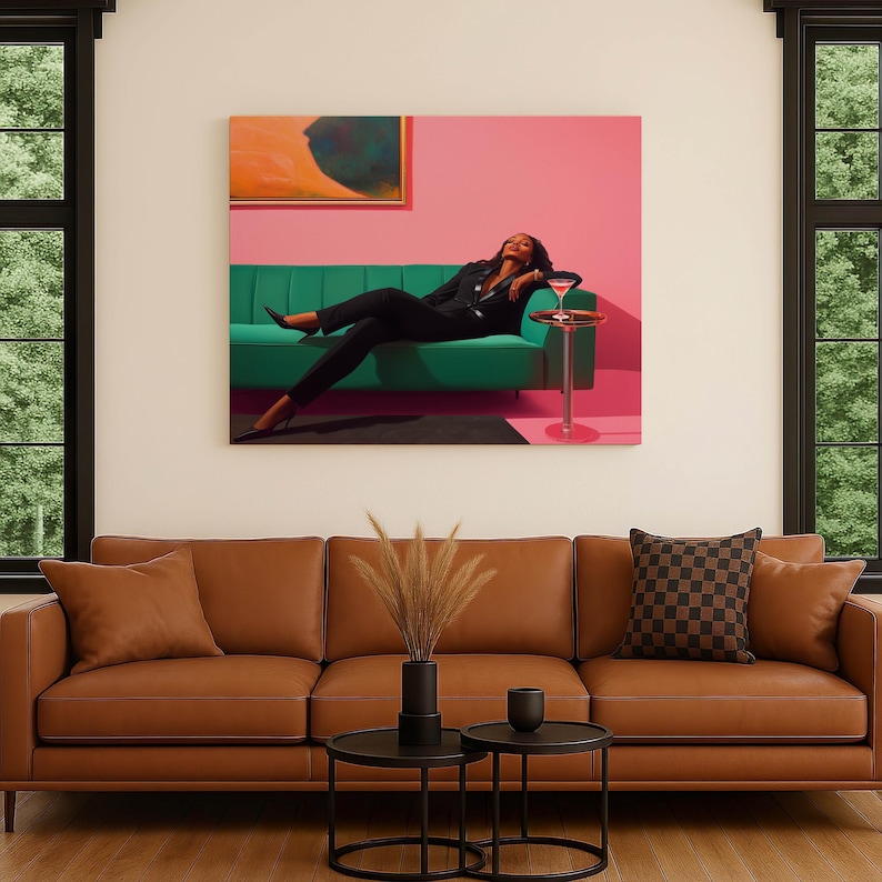 May include: A large canvas art piece depicts a person in a black suit reclining on a green sofa, with a cocktail on a side table. The background is pink, and the art piece is mounted above a brown leather sofa with a checkered pillow.