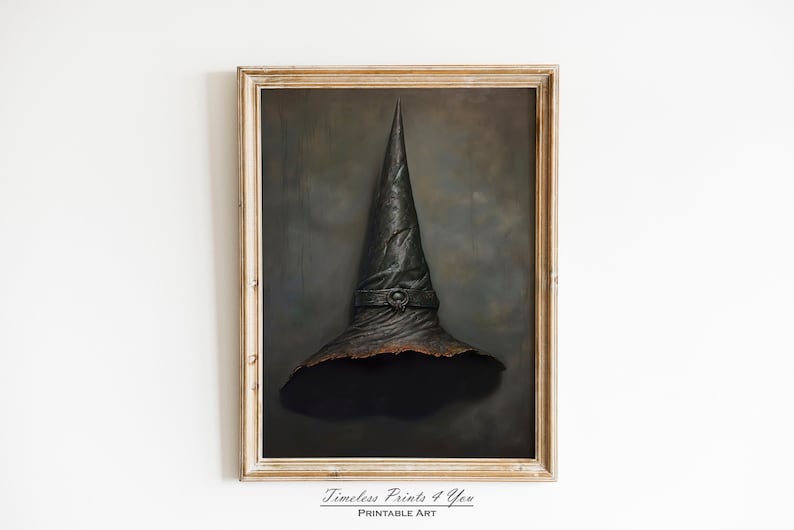 Op de afbeelding: Een ingelijst schilderij van een zwarte heksenhoed met een bruine rand en een puntige top. De hoed is geplaatst tegen een donkergrijze achtergrond met een subtiel wolkenpatroon. De lijst is van licht hout.