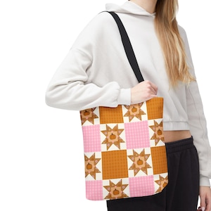May include: A tote bag featuring a repeating patchwork pattern of orange pumpkin icons centered within white star shapes, alternating with solid orange and light pink gingham squares. The bag has a black shoulder strap and a rectangular structure.