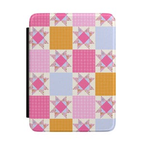 Op de afbeelding: Een rechthoekige hoes met een patchwork-ontwerp. Het patroon heeft vierkanten in roze, lichtblauw en goud, met stervormige bloemaccenten. Aan de linkerkant zit een zwarte band. De hoes is waarschijnlijk voor een e-reader of tablet.