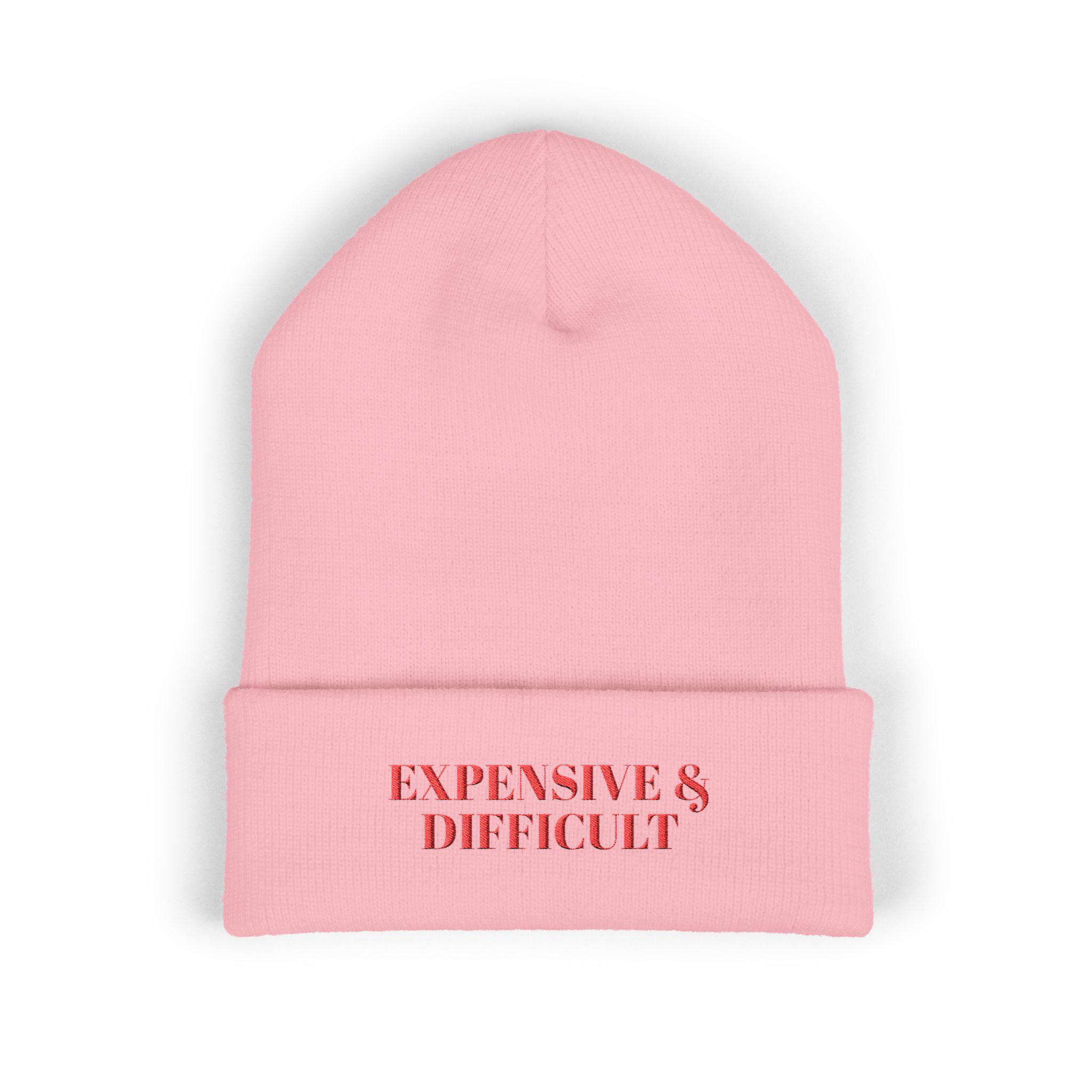 May include: A light pink beanie with the words "EXPENSIVE & DIFFICULT" in red block letters across the front. The beanie is made of a soft, knitted material and is a solid color.