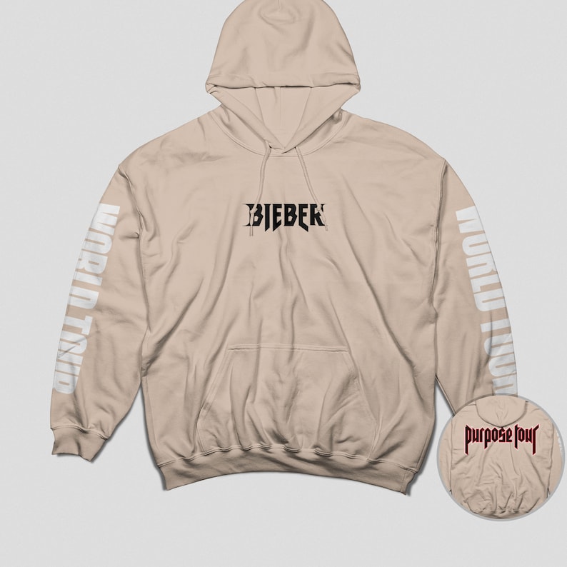 May include: A beige hoodie with the text "BIEBER" in black on the front and "WORLD TOUR" in white on the sleeves. The hoodie has a drawstring hood and a kangaroo pocket.
