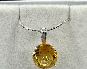 Puede incluir: Un collar de cadena de plata con un colgante de citrino amarillo redondo y grande.