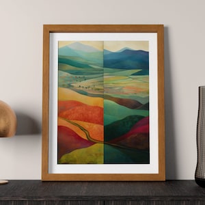 Op de afbeelding: Een ingelijst abstract landschapschilderij met een gesplitst beeld van een kleurrijke vallei. De linkerkant van het schilderij toont een kronkelende weg door een vallei met tinten rood, oranje, geel en groen. De rechterkant van het schilderij toont een vallei met tinten groen, blauw en paars.