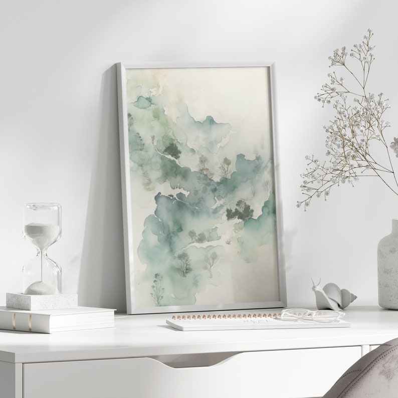 May include: A framed watercolor painting of a landscape with green and blue hues. The painting depicts a misty forest with trees and hills.