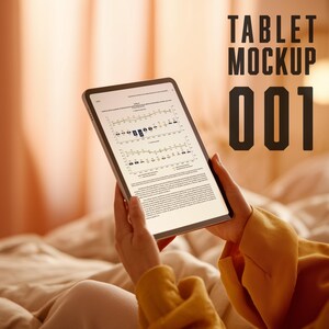 May include: A tablet with a bright screen displaying charts and text is held by a person. The tablet has a dark border and is set against a soft, blurred background. The text "TABLET MOCKUP 001" is displayed in large, bold letters.