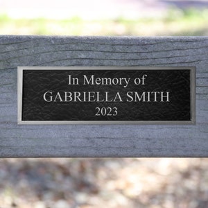 May include: A black plaque with silver trim reads "In Memory of GABRIELLA SMITH 2023".