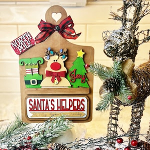May include: Wooden Christmas sign with a red and green elf, a reindeer, a Christmas tree, and the words "North Pole" and "Santa's Helpers".