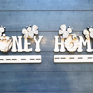 May include: Wooden honey bee themed wall decor with the words "Honey Home" and two bee figures. The decor has a shelf for hanging items.
