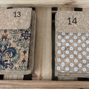 Pode incluir: Duas carteiras de corti&ccedil;a com padr&otilde;es diferentes. A carteira &agrave; esquerda tem um padr&atilde;o floral em tons de azul, verde e marrom. A carteira &agrave; direita tem um padr&atilde;o de margarida branca em um fundo de corti&ccedil;a. A carteira &agrave; esquerda tem o n&uacute;mero 13 na frente e a carteira &agrave; direita tem o n&uacute;mero 14 na frente.