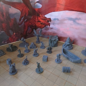 May include: A collection of gray 3D printed miniature figures and objects, including a dragon, a boat, a chest, barrels, and various fantasy creatures. The miniatures are arranged on a gray and white gridded surface.