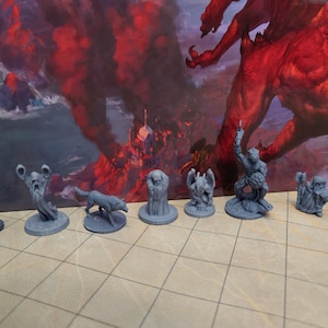 May include: A set of nine miniature figurines, painted in a gray color, depicting various fantasy creatures and characters. The figurines are displayed on a gray and white checkered surface.