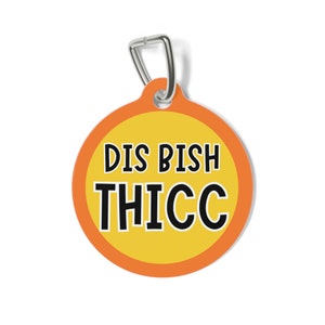 May include: A round orange and yellow tag with a silver ring. The tag says "DIS BISH THICC" in black text.