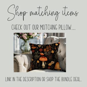 May include: A black cushion with a floral pattern featuring mushrooms, leaves, and flowers in shades of orange, yellow, and red. The cushion is sitting on a white armchair.