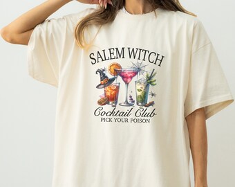 May include: A white t-shirt with a graphic design featuring a witch hat, three cocktails, and the text "Salem Witch Cocktail Club Pick Your Poison".