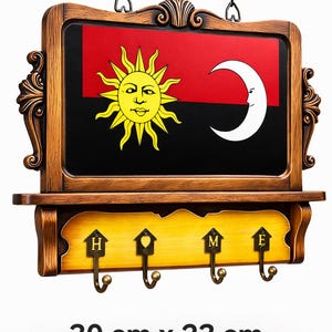 May include: Wooden wall-mounted key holder with a decorative frame. The design features a black and red background with a yellow sun and white crescent moon. Includes four hooks and the word "HOME". Measures 30 cm x 23 cm.