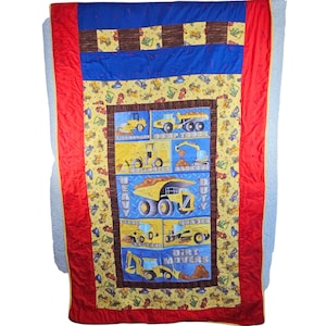 May include: A colorful quilt featuring a construction theme. The quilt has a red border, blue and brown stripes, and a central panel with yellow construction vehicles. The words "Heavy Duty" and "Dirt Movers" are visible.