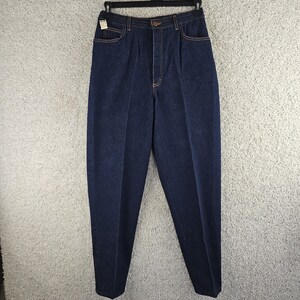 Può includere: Jeans in denim blu scuro a vita alta con design frontale plissettato, chiusura con bottone e cerniera, due tasche laterali e cuciture a contrasto arancioni su tutto il capo. I jeans presentano una silhouette a gamba affusolata e lavaggio scuro.