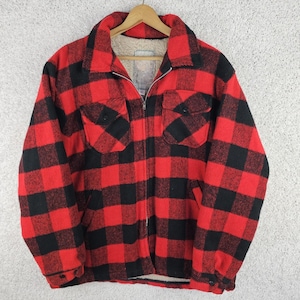 May include: A red and black checked jacket with a full zip and two chest pockets. The jacket has a soft, white interior lining and a collared neckline. The jacket is hanging on a wooden hanger.