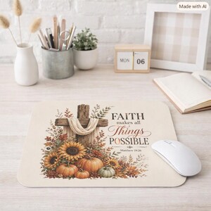 May include: A rectangular mouse pad featuring a wooden cross draped in fabric, surrounded by sunflowers, pumpkins, and autumn foliage. The text reads: FAITH makes all Things POSSIBLE Matthew 19:26. The design is printed on a light cream background.