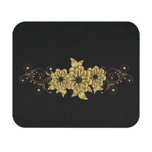 May include: Black mousepad with a gold floral pattern. The design features three large flowers with detailed petals, surrounded by smaller flowers and swirling vines. The mousepad has rounded corners.