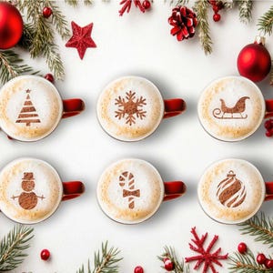 May include: Six red-handled mugs of coffee with festive latte art, including a Christmas tree, snowflake, sleigh, snowman, candy cane, and bauble. The mugs are surrounded by Christmas decorations, including baubles and pine branches.