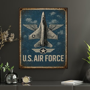 May include: A vintage-style metal sign featuring a detailed illustration of a jet fighter with wings, set against a blue sky background with clouds. The words "U.S. AIR FORCE" are prominently displayed in white lettering below the aircraft.