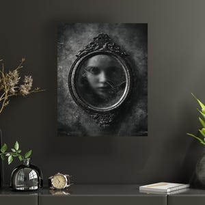 May include: A black and white artwork featuring an oval mirror with an ornate frame. The mirror reflects a blurred face, with cracks across the glass. The background is a textured, dark gray, creating a gothic or horror theme.