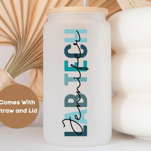 May include: Frosted glass tumbler with a wooden lid and straw. The tumbler features the text "LAB TECH" in teal and black, with the name "Jennifer" in a script font. The tumbler is designed for cold beverages.