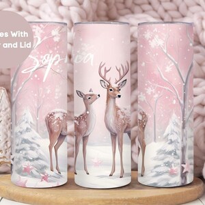 May include: A pink and white stainless steel tumbler with a winter scene featuring two deer in a snowy forest. The tumbler has the name "Sophia" written on it.