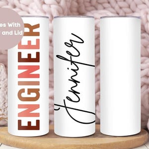 May include: Three white stainless steel tumblers with different designs. The first tumbler has the word "ENGINEER" in brown, pink, and orange letters. The second tumbler has the name "Jennifer" written in black cursive. The third tumbler is blank.