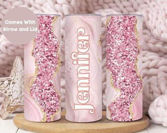 May include: Three pink and gold glitter tumbler cups with a marbleized design. The middle cup has the name "Jennifer" written on it in white letters.