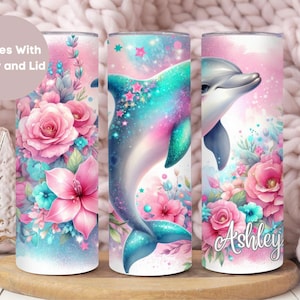 May include: Three stainless steel tumblers with a pink, blue, and green floral design and a dolphin. The tumbler on the right has the name "Ashley" written on it.