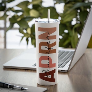 May include: A white stainless steel tumbler with a brown, pink, and orange design that says "APRN Jennifer".